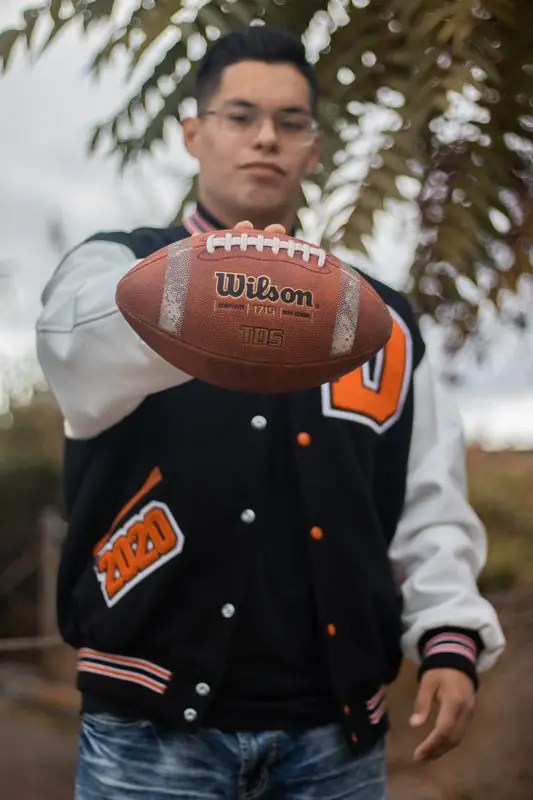 Person in a varsity jacket holding a football