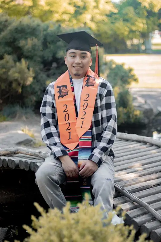 Graduate sitting on a wooden bridge