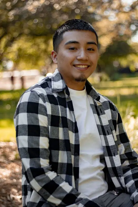 Person in a checkered shirt smiling outdoors