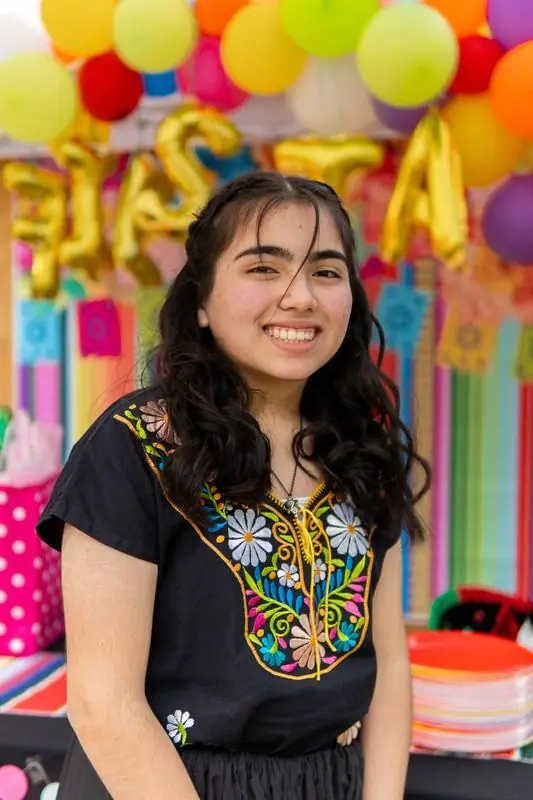 Smiling person in an embroidered shirt at a festive event