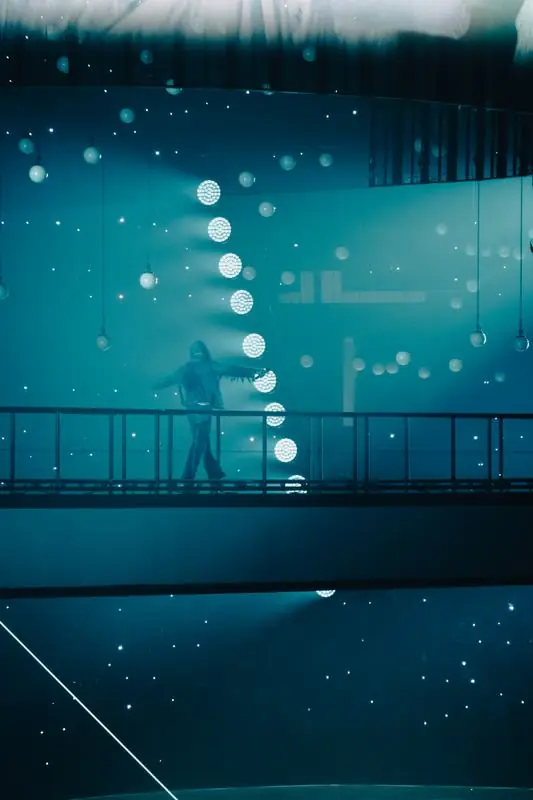 Performer on a walkway among spherical lights
