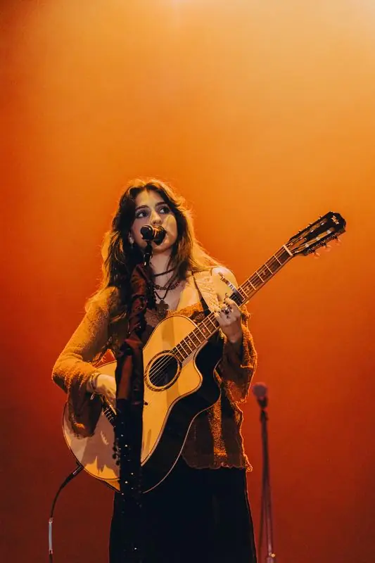Singer playing acoustic guitar under amber light