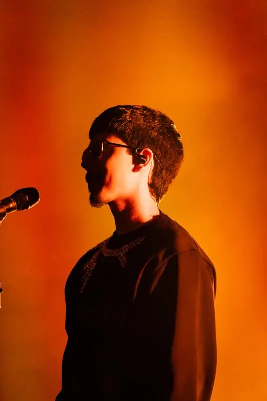 Singer in profile against an orange background