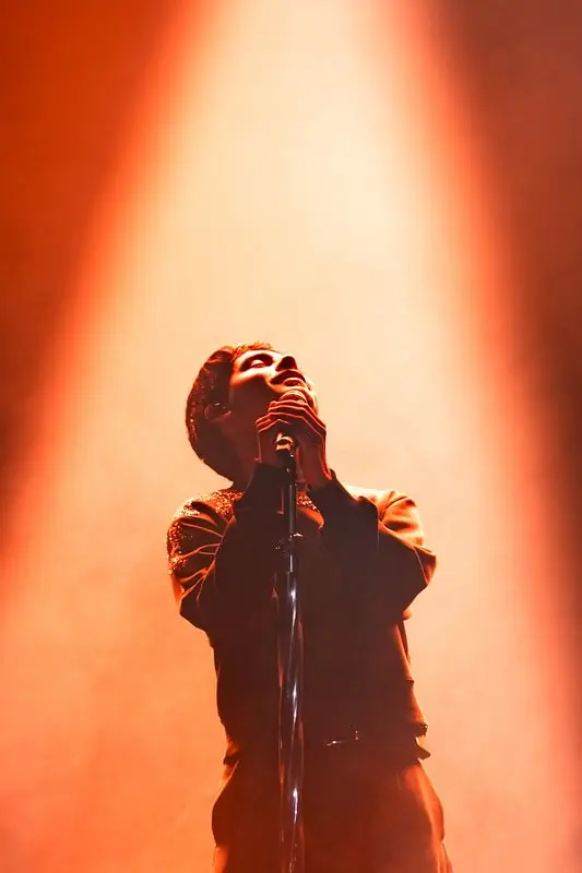 Performer singing under warm orange light
